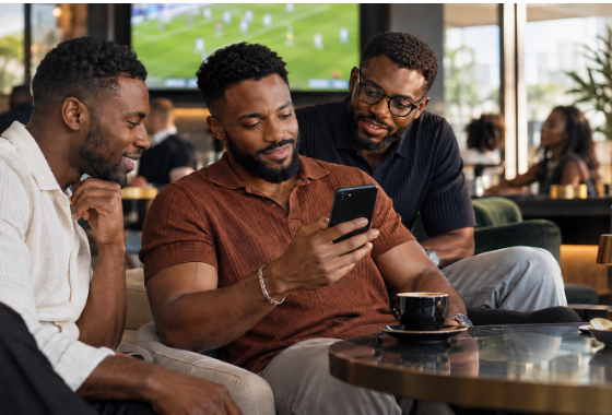 Trois hommes regardent un téléphone pendant un match de football